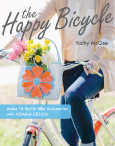 book cover with a woman riding a bike with a bag of flowers on the&hellip;